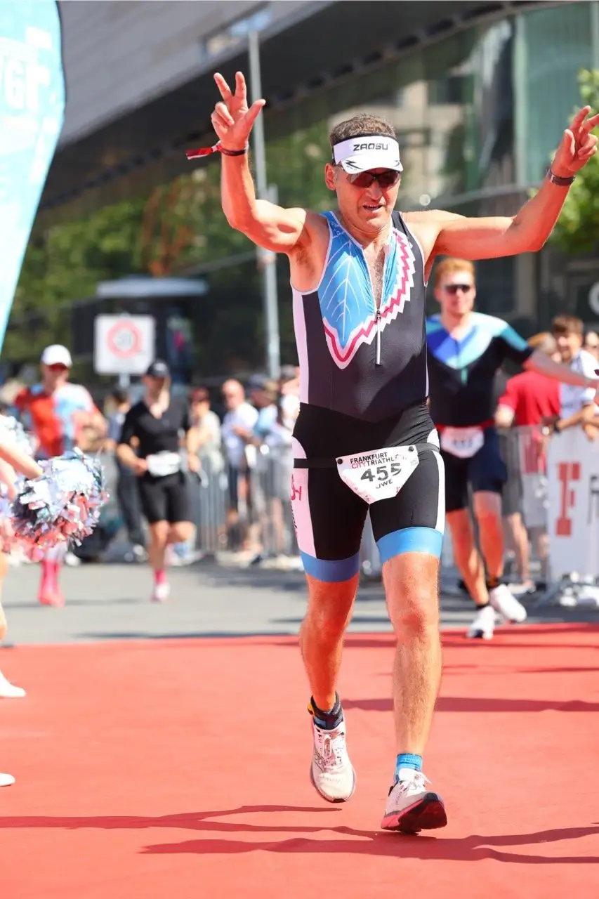 Uwe jubelt mit erhobenen Armen im Ziel des Frankfurt City Triathlon